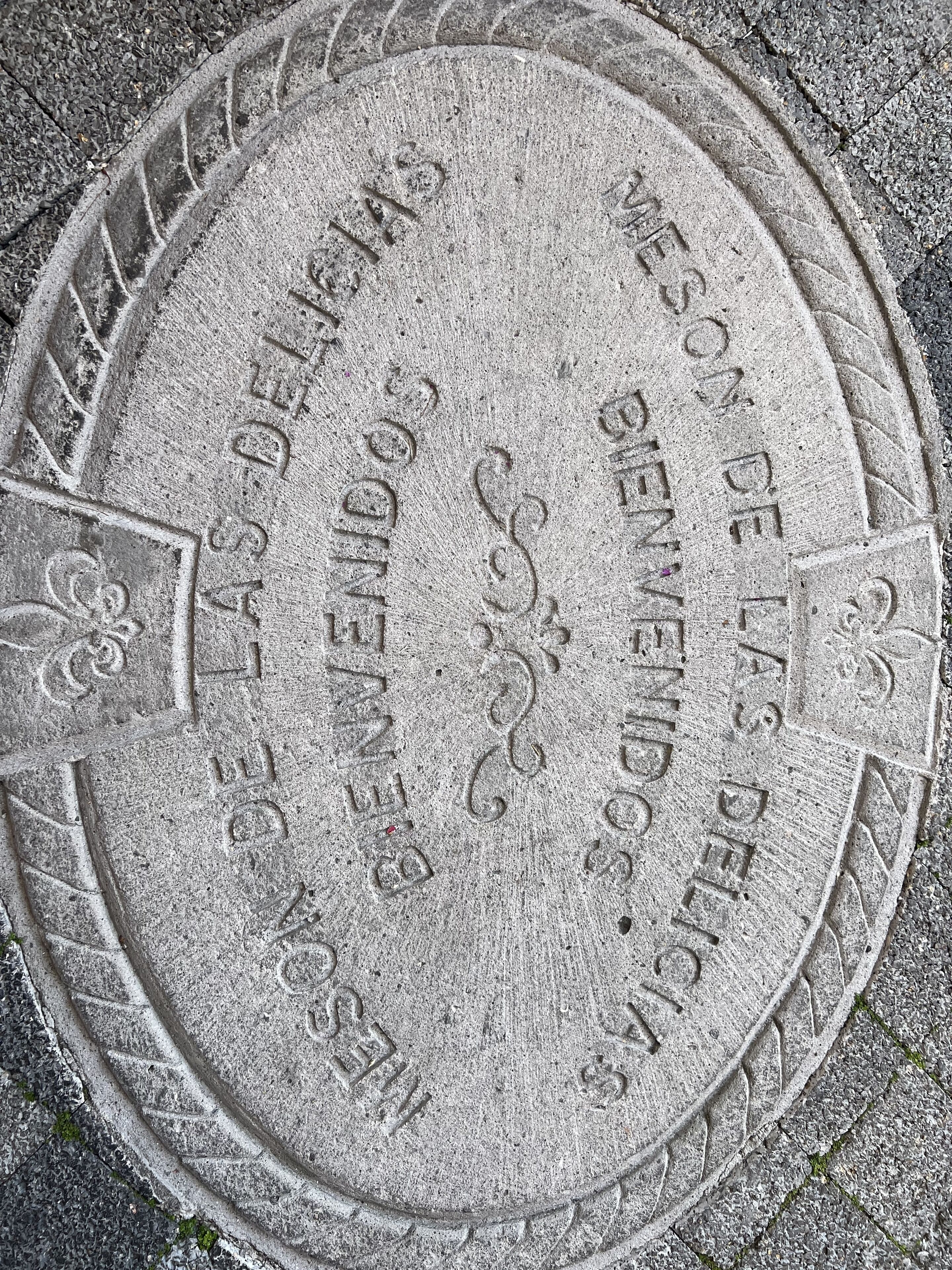 Una tapa de alcantarilla redonda con texto y símbolos en relieve.
