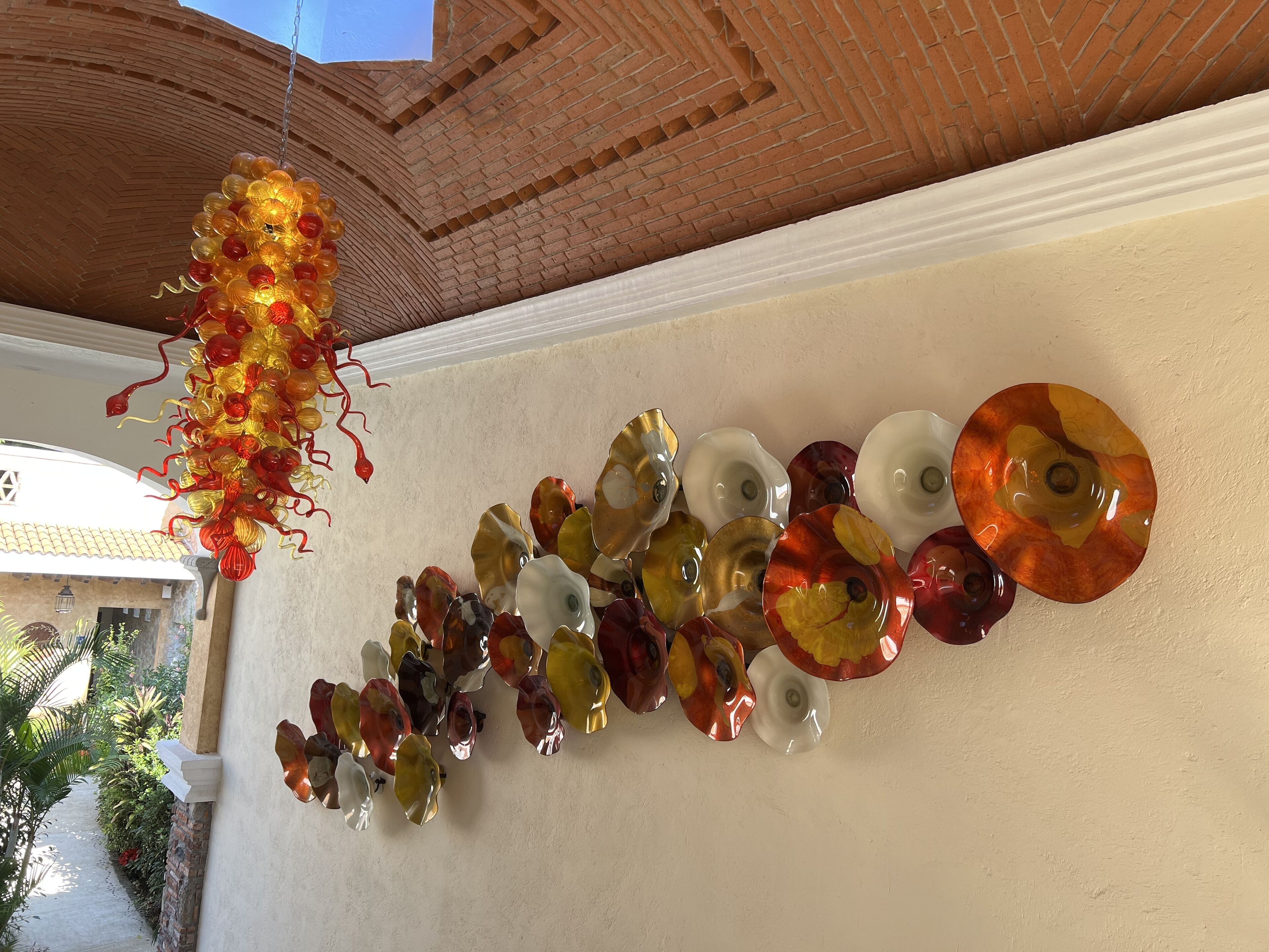 A ceiling with a hanging glass ornament and a row of glass plates.