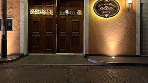 A hotel entrance with double doors, a decorative sign above the doors, and a wall-mounted light fixture. - Mesón de las Delicias (Cuernavaca)