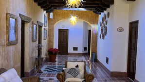 A hotel lobby with a checkered floor, a sofa, armchairs, a coffee table, and a chandelier. - Mesón de las Delicias (Cuernavaca)