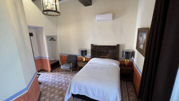Habitación de hotel con una cama grande, una silla, un escritorio, una lámpara y una lámpara colgante.