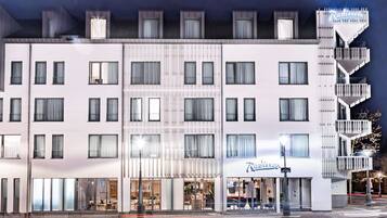 Un hôtel à plusieurs étages, doté d’une façade moderne, de grandes fenêtres et d’un escalier imposant situé sur le côté droit.