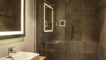 A modern bathroom with a large mirror, a sink, and a shower area.
