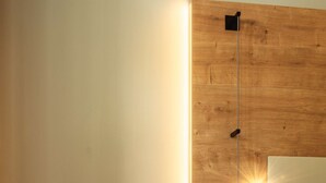 A modern room with a wooden accent wall, a standing lamp, a round side table, and a dark upholstered chair. - Radisson Hotel Liege City Centre (Liege)