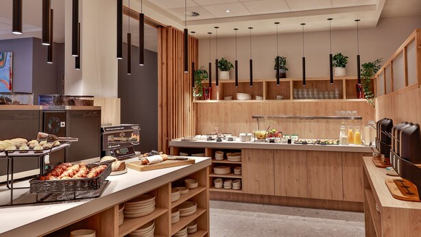 A modern kitchen area with wooden cabinets, a buffet counter, and hanging pendant lights. - Radisson Hotel Liege City Centre (Liege)