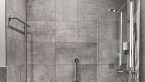 A modern shower area with a glass door, a handheld showerhead, and a handheld showerhead on the right. - Radisson Hotel Liege City Centre (Liege)