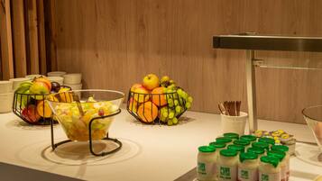 Uma mesa de buffet com diversos alimentos, incluindo frutas, salada e acompanhamentos.