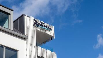 Een modern gebouw met een uniek architectonisch ontwerp, met een opvallend balkon en een helderblauwe lucht op de achtergrond.