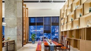 A modern interior with a long wooden table and chairs, a marble floor, and a view of the street through large windows. - Mandao Hotel (Nanbu County)