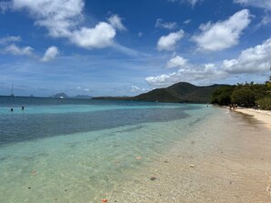 A beach with clear turquoise water, a sandy shore, and a distant mountain. - House in a private residential complex with a swimming pool and beach access (Les Trois-Îlets)