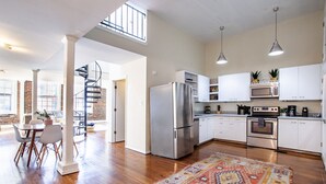 Una cocina amplia con electrodomésticos modernos, un comedor con techos altos y una escalera que conduce a un nivel superior.