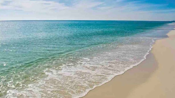 A beach with clear turquoise water and a sandy shore.