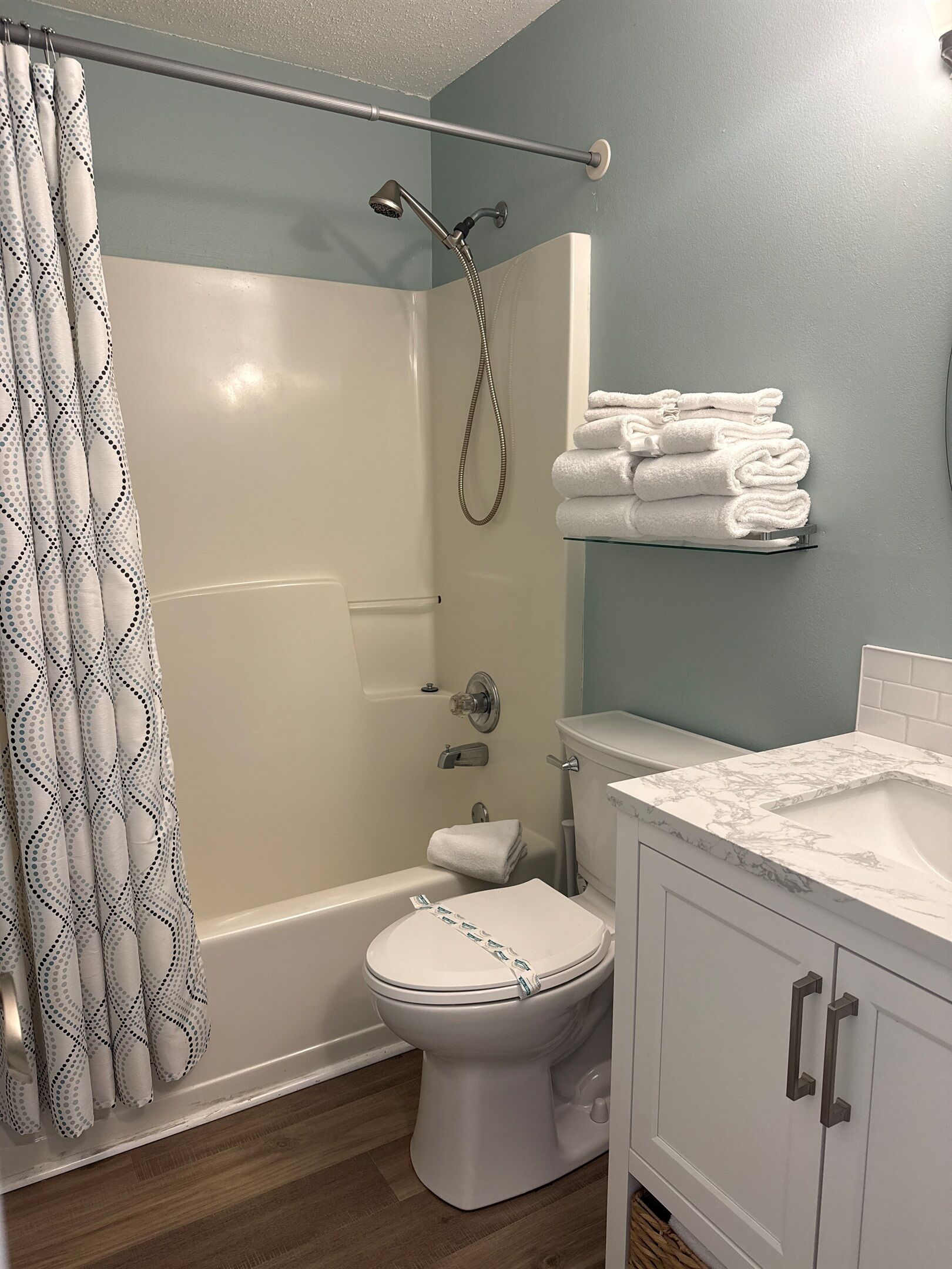 A bathroom with a shower, toilet, and sink.