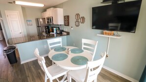 A dining area with a round table, four chairs, and teal placemats.