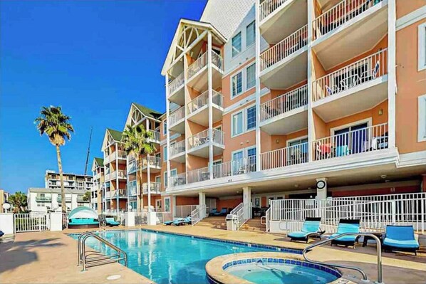 Un h ôtel à plusieurs étages doté de balcons, d’une piscine et de chaises longues.