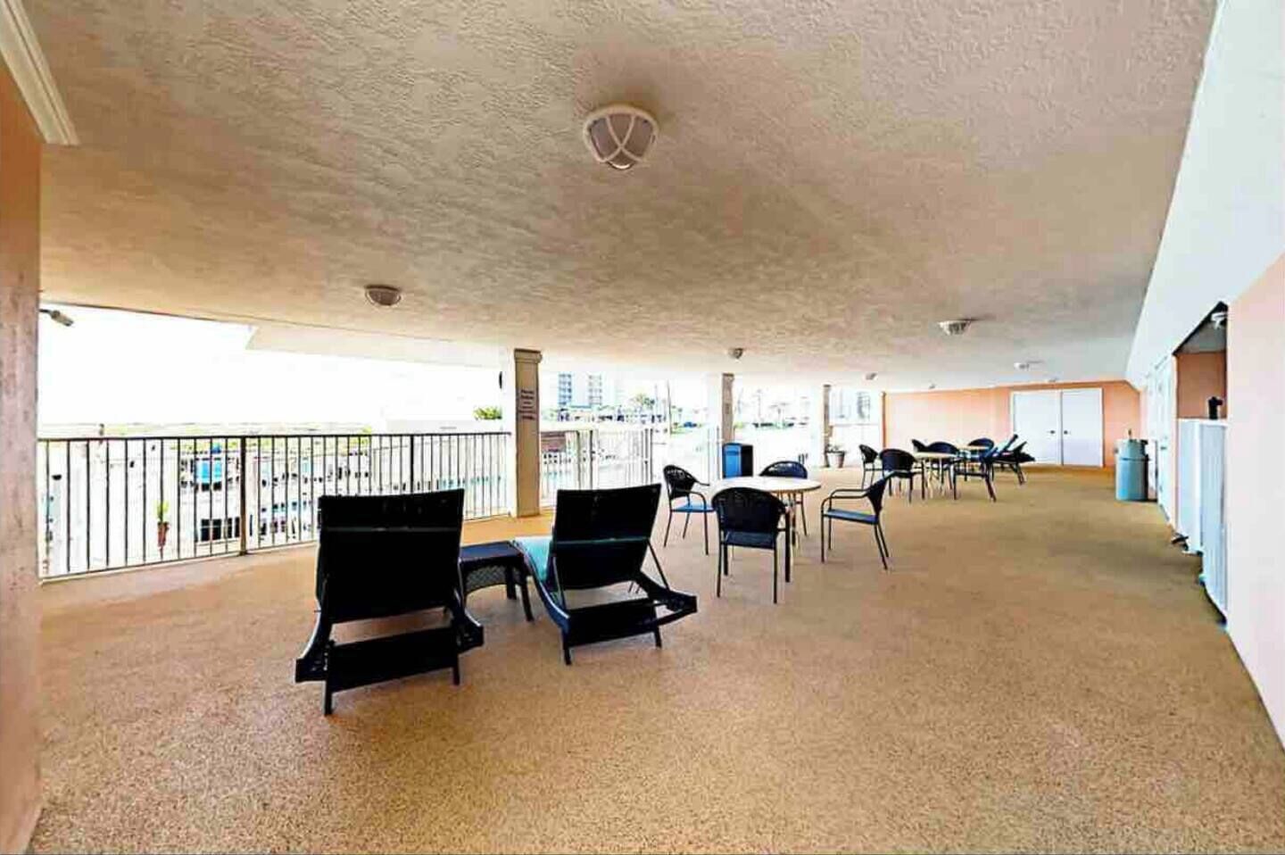 A spacious balcony area with several chairs and tables, a view of the cityscape, and a ceiling with a unique design.