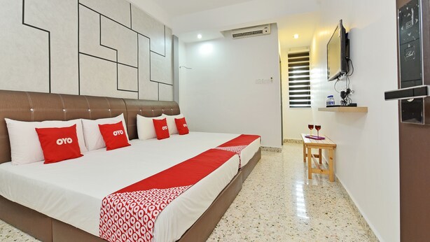 A hotel room with a large bed, a TV mounted on the wall, and a small table with glasses. - OYO Home 90427 Mm Homestay (Segamat)