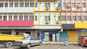 A parking lot with a white car and a yellow truck. - OYO Home 90427 Mm Homestay (Segamat)