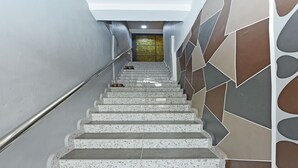 A staircase with a metal handrail, leading to a landing with a glass door. - OYO Home 90427 Mm Homestay (Segamat)