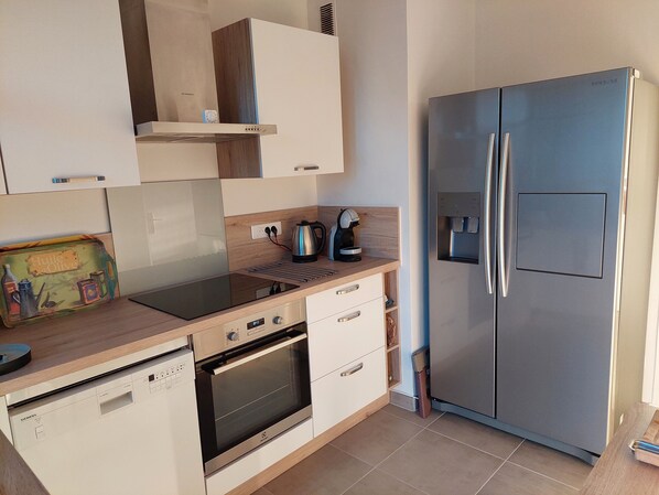 A modern kitchen with a stainless steel refrigerator, built-in oven, and a coffee maker on the countertop.