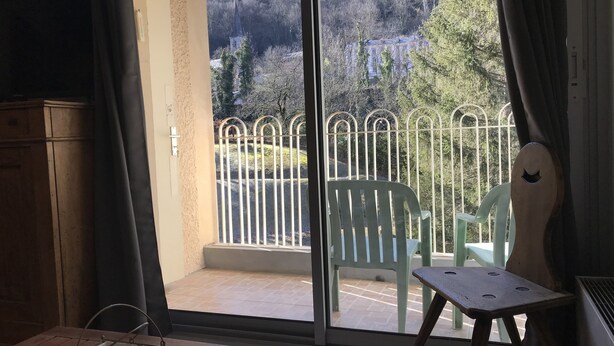 Una habitación con vista a un paisaje montañoso a través de un balcón con barandilla de metal.