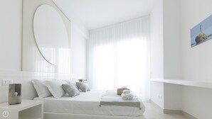 Un dormitori modern amb un llit gran, una taula de nit, un mirall i un quadre a la paret.