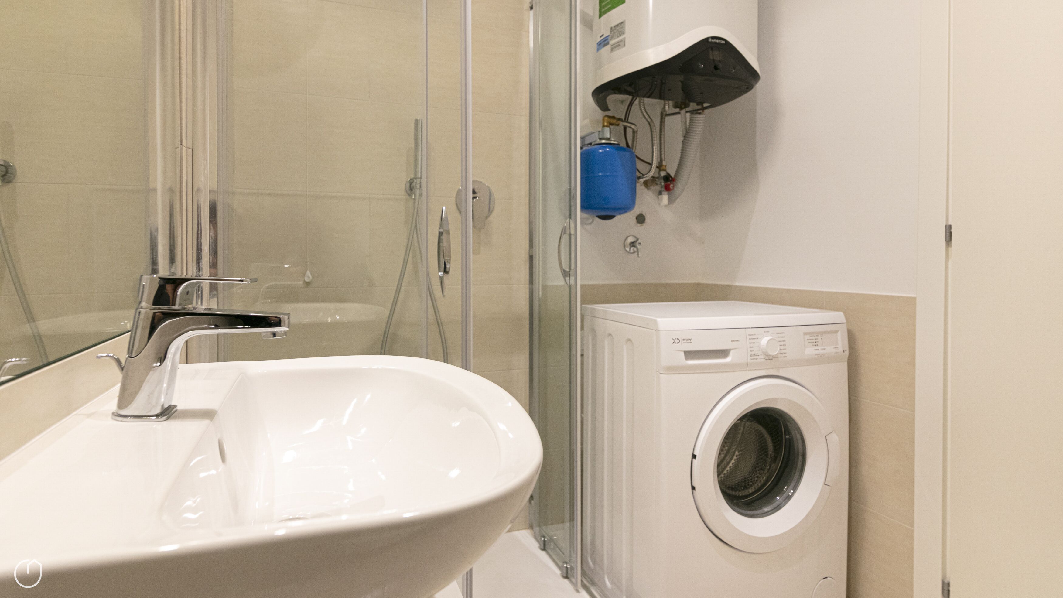 A bathroom with a white sink, a glass shower enclosure, and a front-loading washing machine.