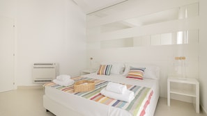 A modern bedroom with a bed, white walls, and a large mirror. - Rivazzurra Homes - 10 (Termoli)