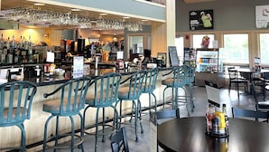 A restaurant with a bar area, seating, and a high ceiling with wooden beams.