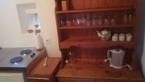 Une cuisine de taille réduite, avec des meubles de rangement en bois, une cuisinière et un petit réfrigérateur.
