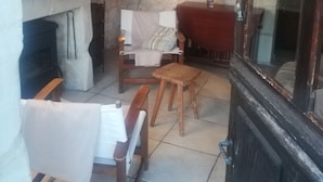 Une pièce chaleureuse avec un mur en pierre, une cheminée, un banc en bois, une chaise et une table.
