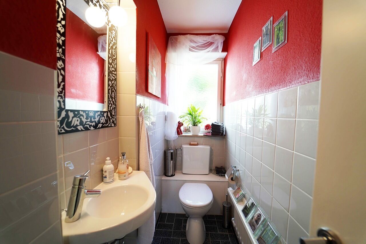 Een kleine badkamer met een wastafel, toilet en een klein raam met een plantje.