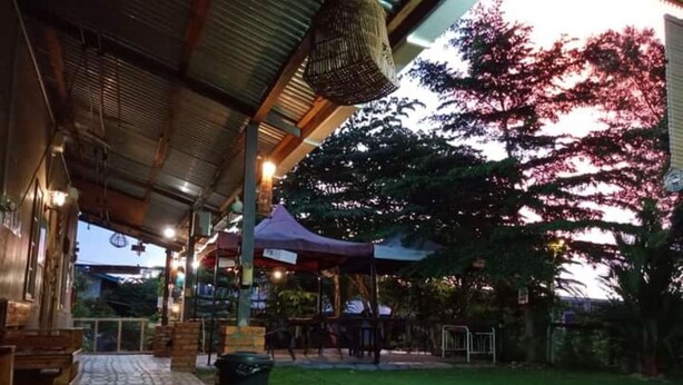 An outdoor seating area with a covered patio, a trash bin, and a grassy lawn. - OYO Home 90426 Kepayan Dnd Stay (Kota Kinabalu)