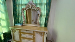 A vanity with a mirror and drawers, set against a green curtain backdrop. - OYO Home 90426 Kepayan Dnd Stay (Kota Kinabalu)