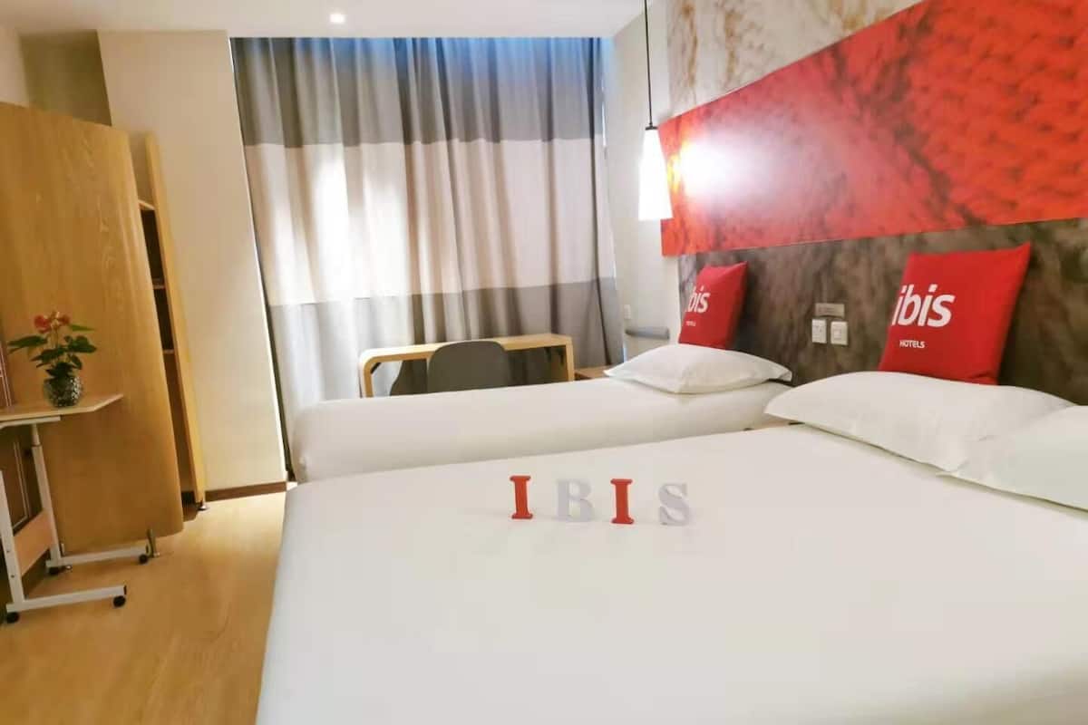 Een hotelkamer met een bed, een bureau, een stoel en een kledingkast.
