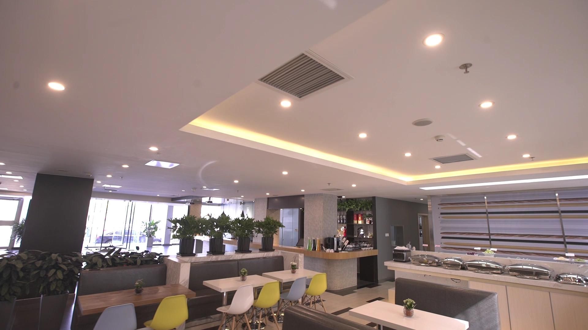 Un restaurante moderno con barra, asientos con sillas coloridas y plantas en macetas.