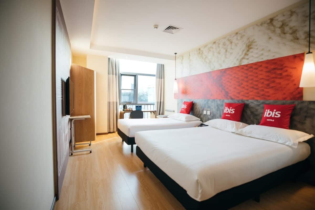 Een hotelkamer met twee bedden, een bureau, een stoel en een televisie.