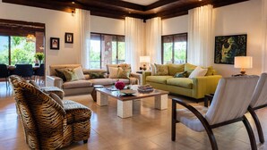 Un amplio salón con sofá, sillones, una mesa de centro y un comedor con sillas y una mesa.
