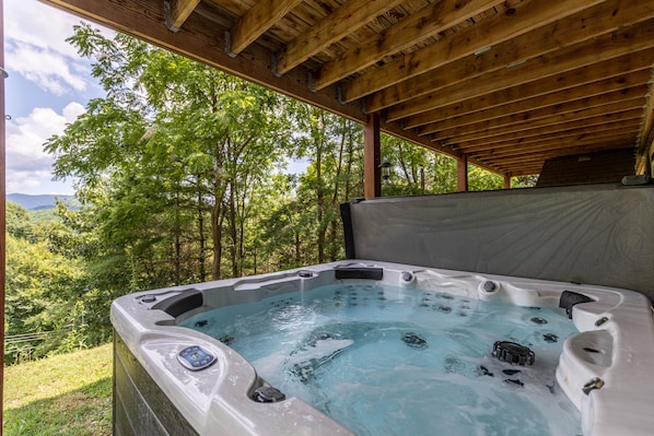 A hot tub with a wooden roof and a view of a forested area.