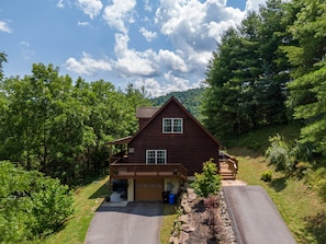 A two-story log cabin with a front porch, a garage, and a driveway.