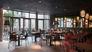 A spacious restaurant with high ceilings, large windows, and a variety of seating arrangements including tables and chairs.