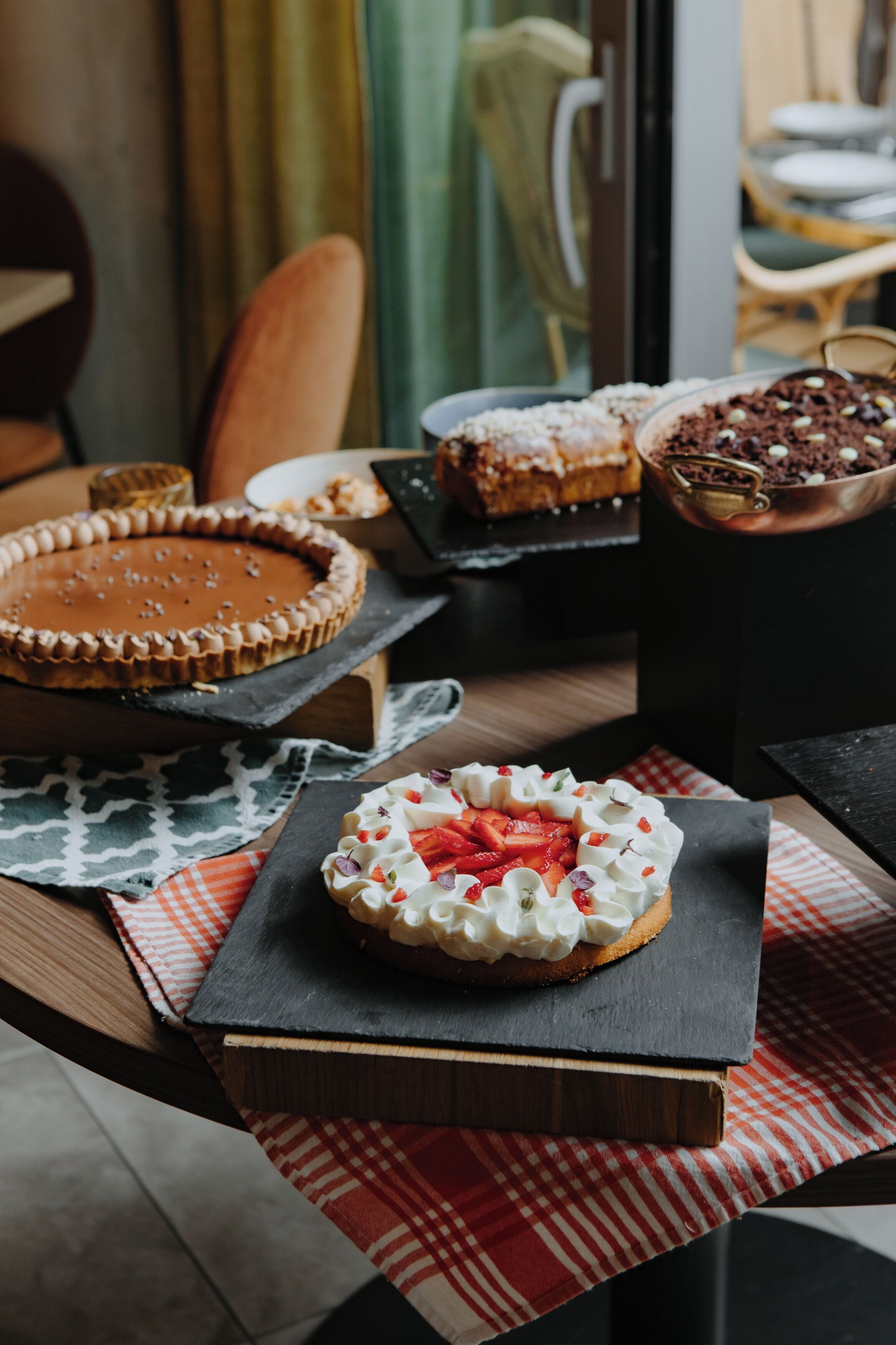 A variety of desserts on a table with a checkered tablecloth.