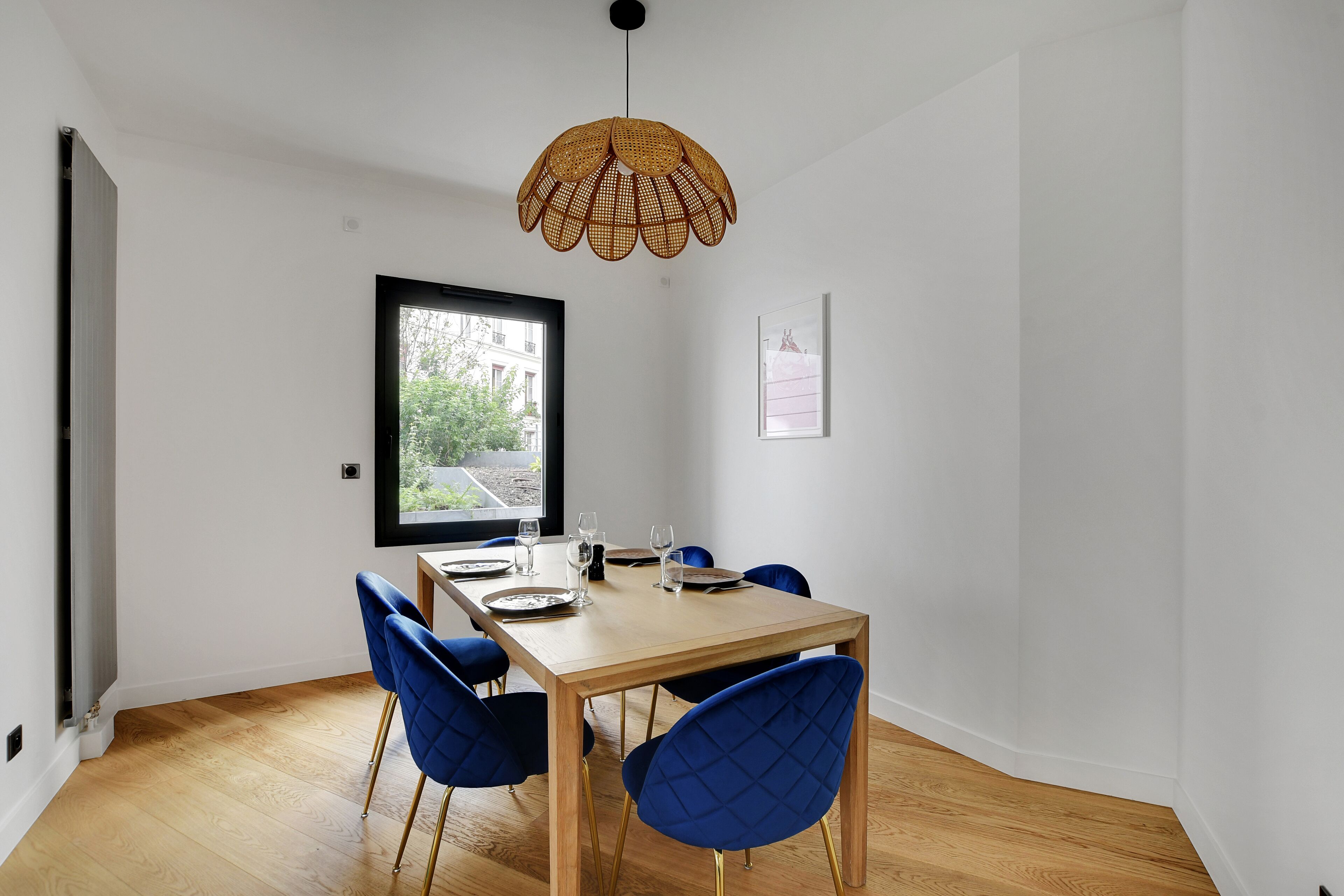 A dining area with a wooden table, blue chairs, and a woven pendant light.