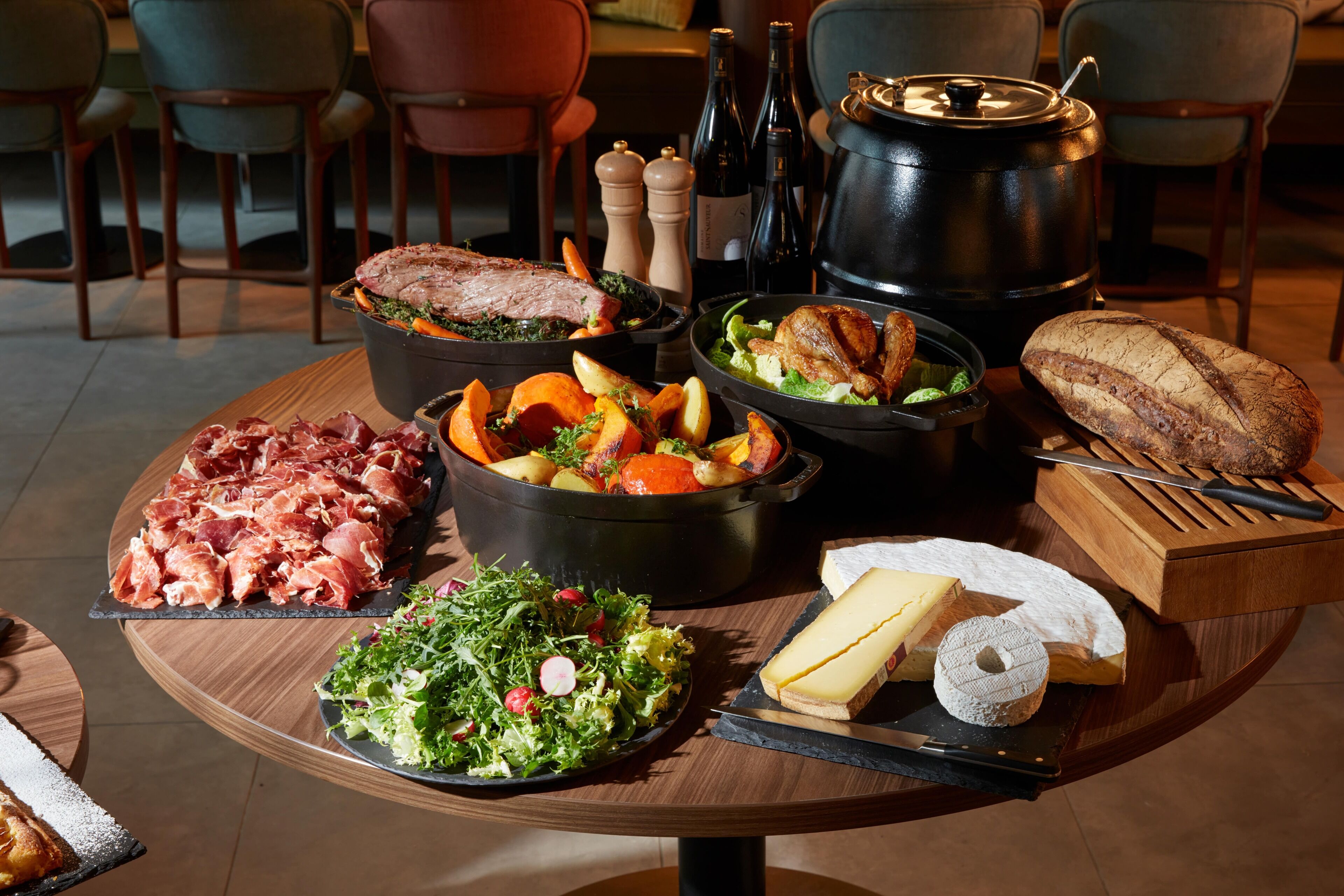 A table with various foods including meats, vegetables, and cheese.