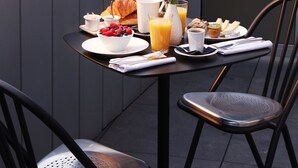 A dining table with breakfast items on a balcony overlooking a cityscape. - Drawing House (Paris)