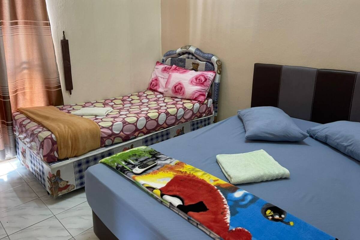 A bedroom with two beds, one with a floral bedspread and the other with a colorful blanket.