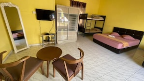 Quarto com cama, televisão, guarda-roupa e uma mesa com cadeiras.