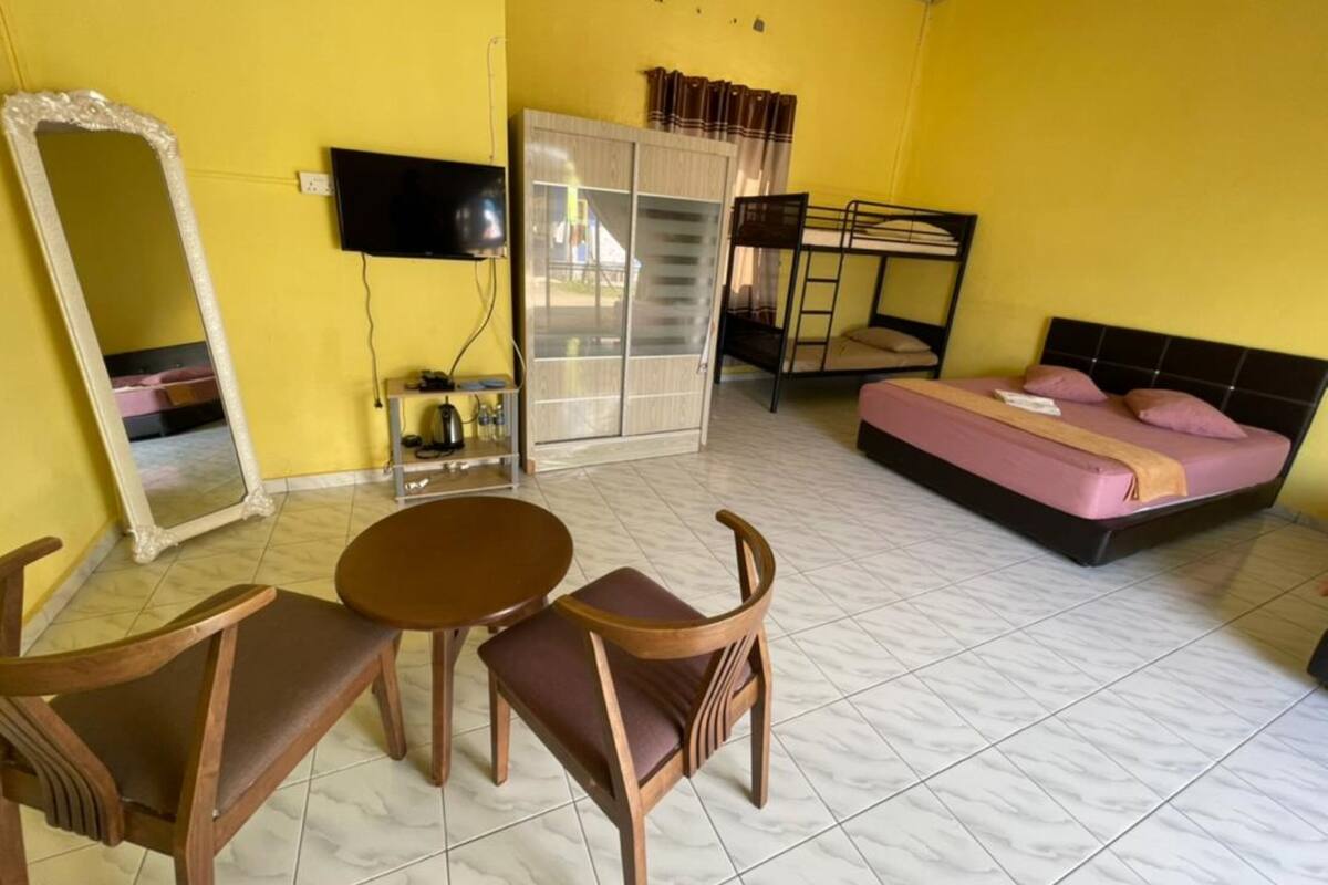 A room with a bed, a TV, a wardrobe, and a table with chairs.