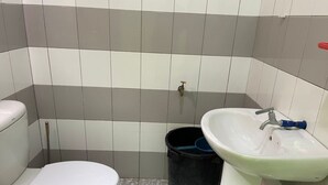 Um banheiro pequeno com vaso sanitário, pia e lixeira preta.