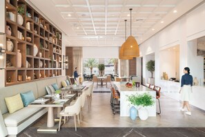 A spacious hotel lobby with a central dining area, a large bookshelf, and a modern ceiling design. - Address Beach Resort Fujairah (Al Aqah)